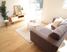 フローリングのリビングに茶色いソファと木でできた丸いローテーブルが置かれている