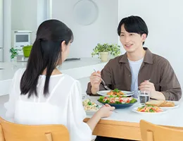 ダイニングで若い男女がサラダとパスタを食べている